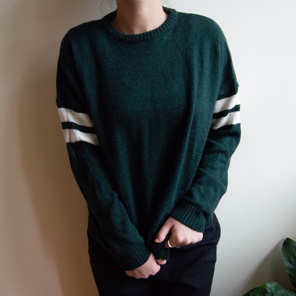 Green sweater with white stripes on the sleeves.